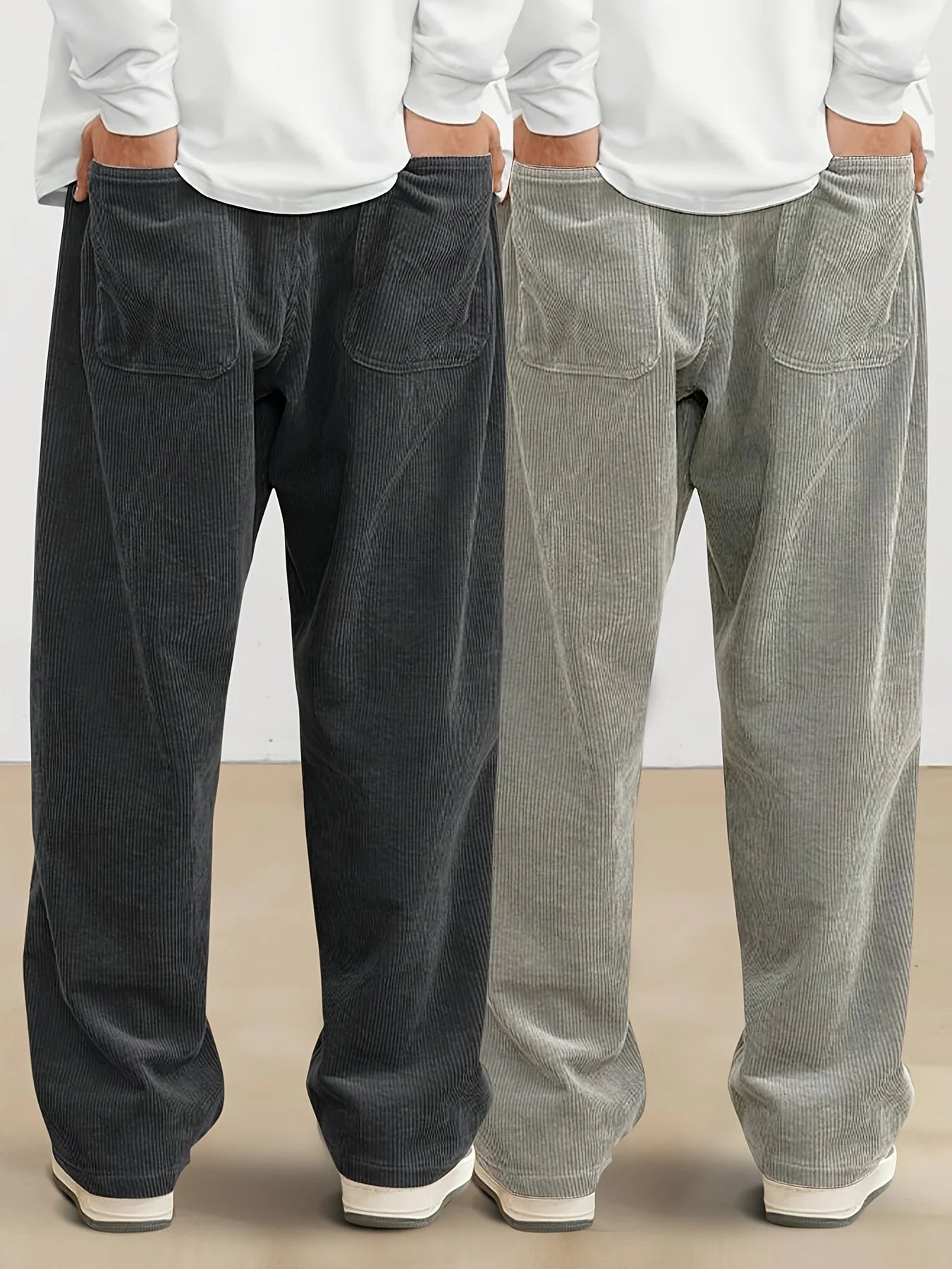 Two pairs of corduroy pants, one black and one gray, on a plain background.