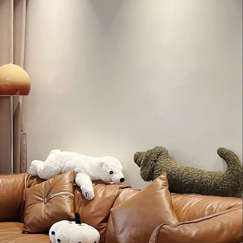 dachshund-shaped cushion on a brown leather sofa against a neutral wall.