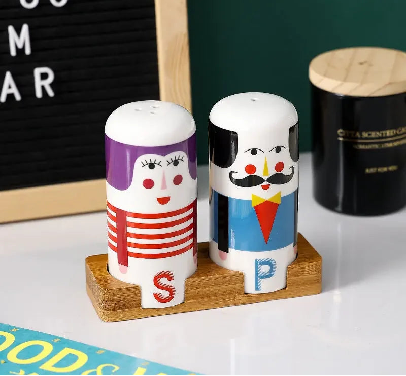 Two cartoon-themed salt and pepper shakers on a wooden stand with a letter board in the background.