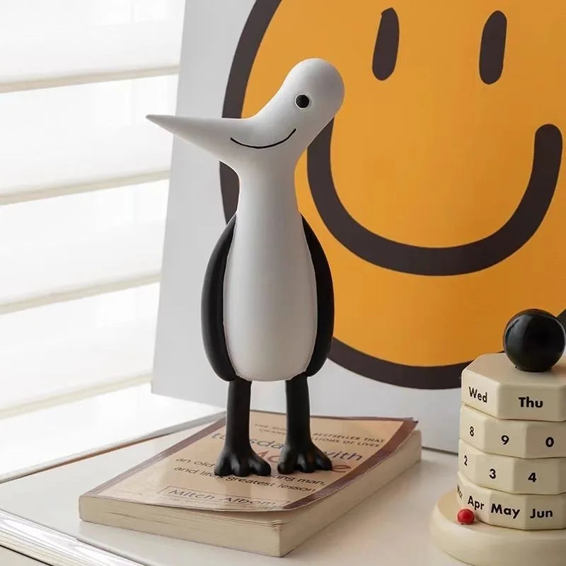 Decorative penguin figure on a book with a smiley face poster in the background