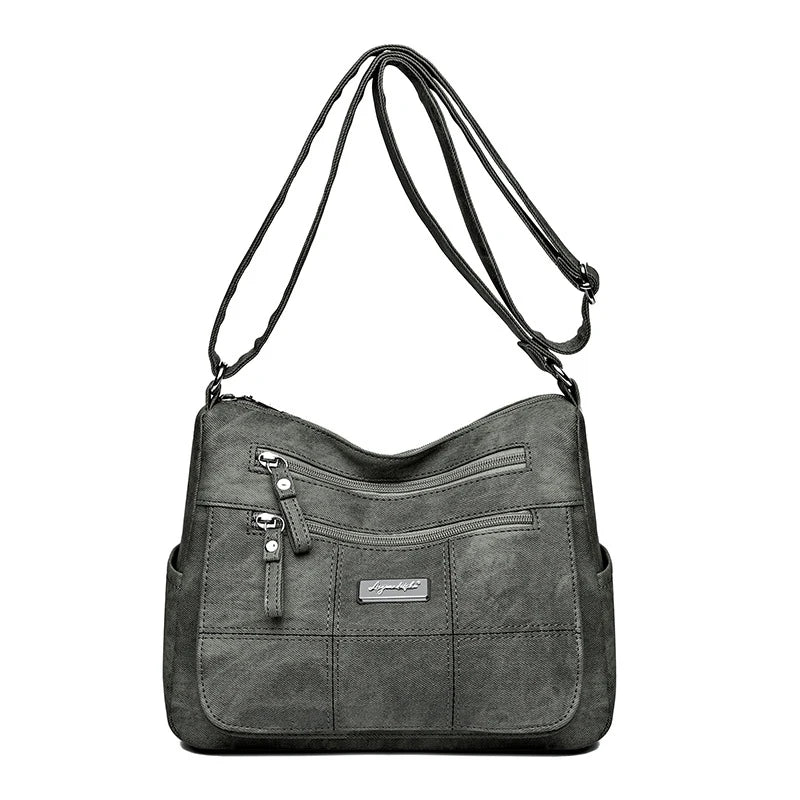Gray shoulder bag with multiple zippers on a white background