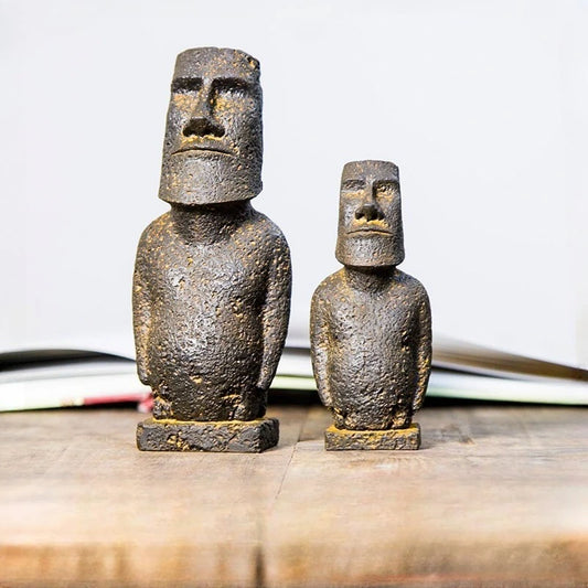 Large and Small Moai-inspired resin ornament with a distressed stone-effect finish displayed on a wooden surface.