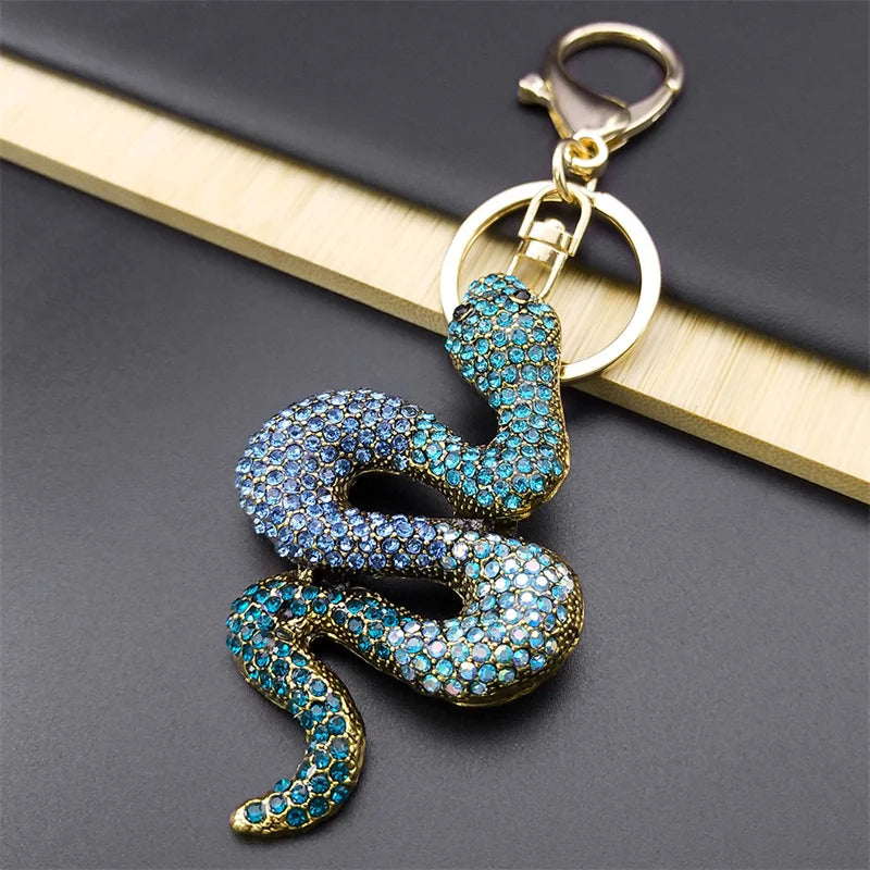 Snake-shaped keychain with blue gemstones on a dark surface