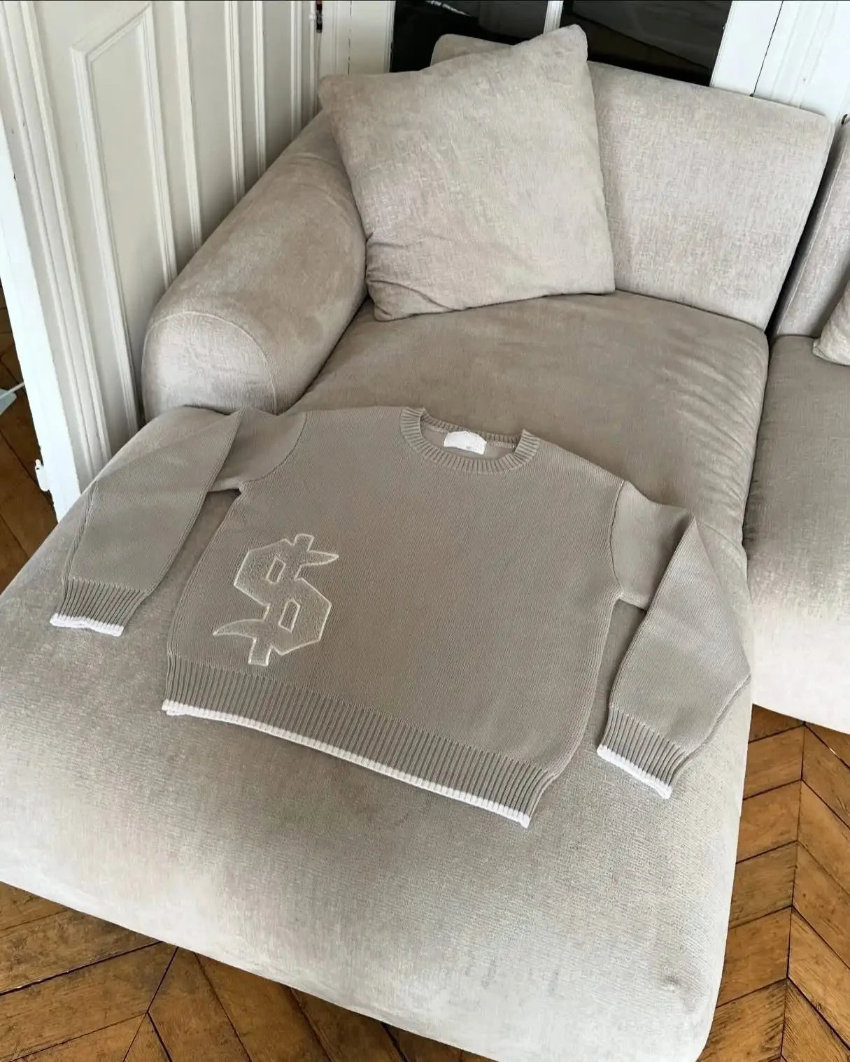 Gray sweater with a logo on a beige sofa