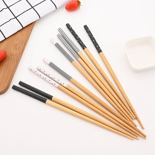 Set of wooden and black pens on a white surface with a wooden cutting board and red strawberry in the background.