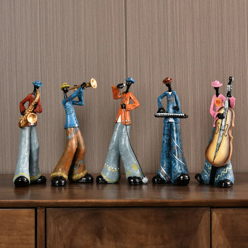 Five colorful figurines of musicians playing instruments on a wooden surface with a striped wall background.