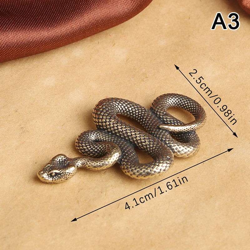 Bronze snake-shaped object with measurements on a beige background