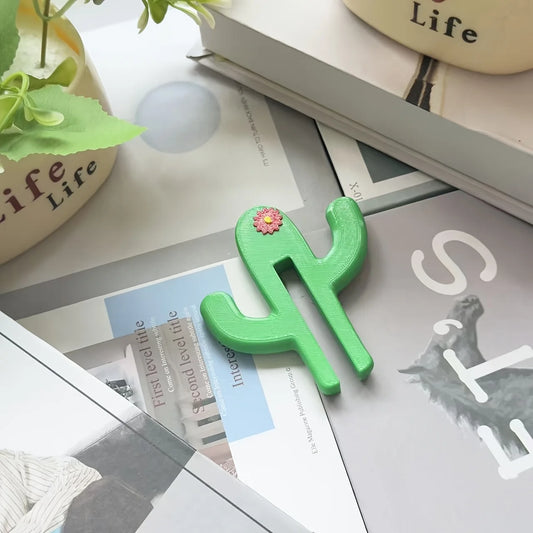 Green cactus-shaped object on a surface with books and a plant