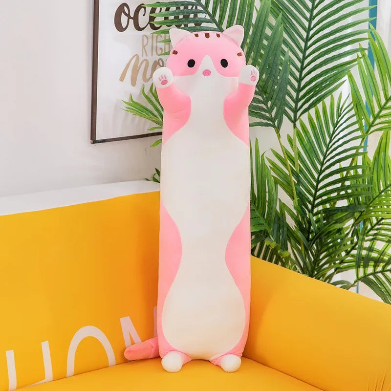 Plushpillow resembling a cat with pink accents on a yellow couch with plants in the background