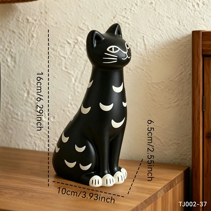 A black cat figurine with white crescent moon patterns, shown sitting on a wooden surface with overlaid dimension lines and text indicating its height, width, and depth.