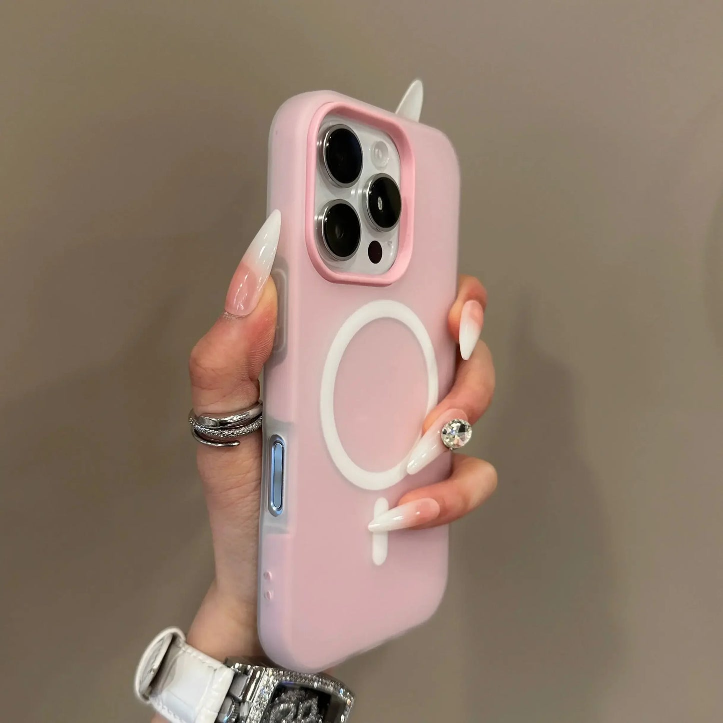 Hand holding a pink phone case with a white logo on a neutral background