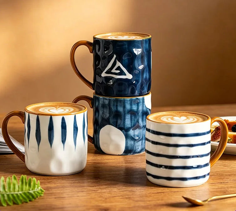 Three ceramic mugs with different designs on a wooden surface