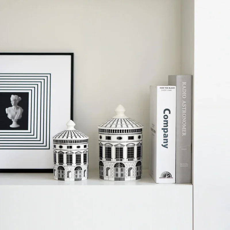 Decorative jars with architectural design on a shelf next to a framed black and white photo and books.