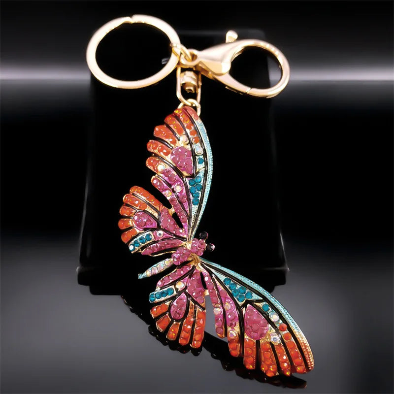 Colorful butterfly-shaped keychain with a gold clasp on a black background