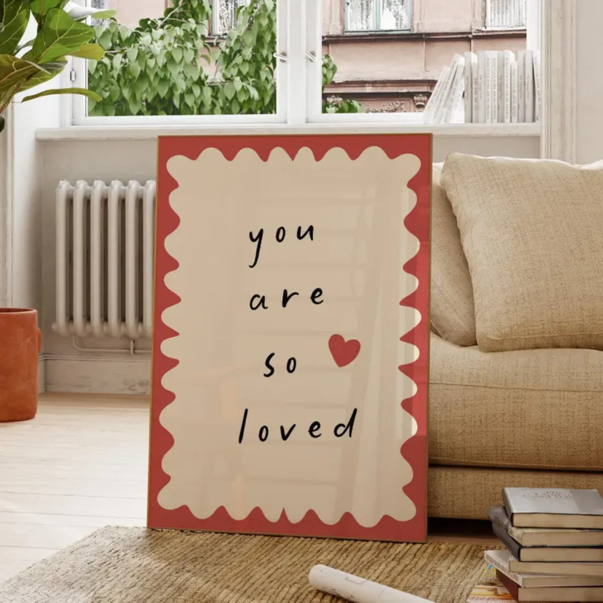 Decorative sign with 'you are so loved' text in a living room setting