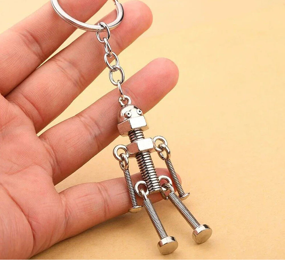 Metallic robot keychain held in a hand against a beige background
