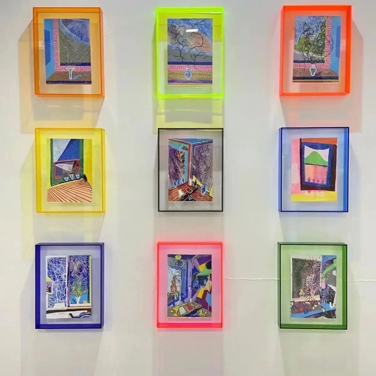 Nine acrylic photo frames arranged in a 3x3 grid on a white wall, each with a different colored frame including orange, green, red, yellow, blue, pink, and green.