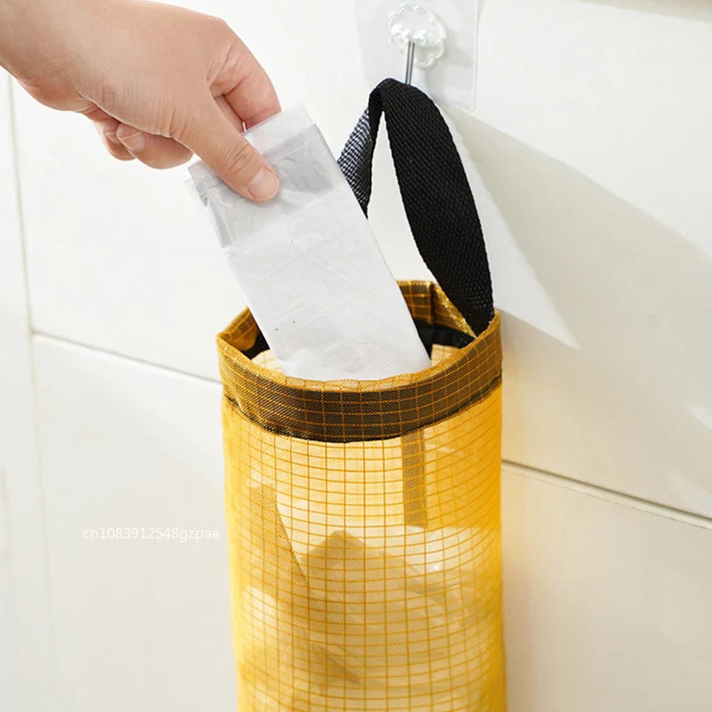 Yellow mesh trash bag with a black handle being pulled out of a trash can.
