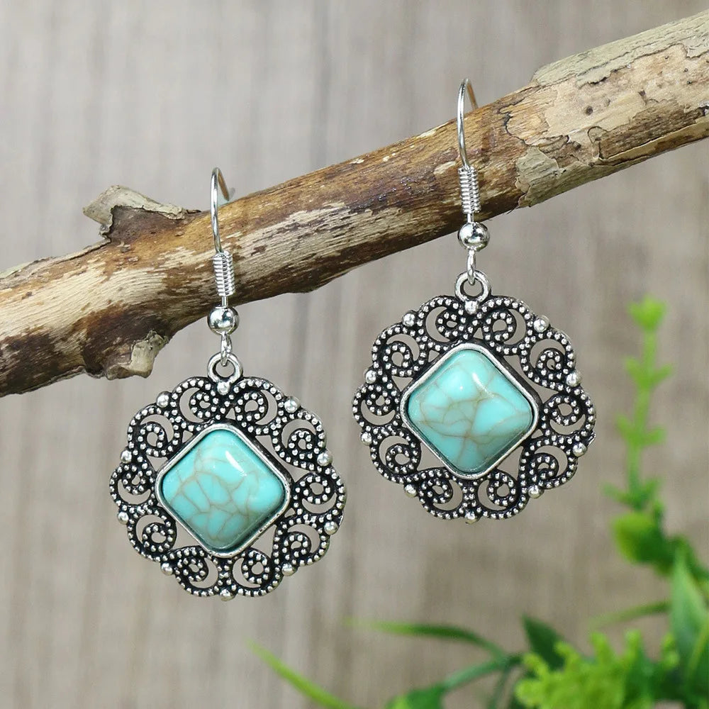 Turquoise earrings with silver filigree on a wooden branch