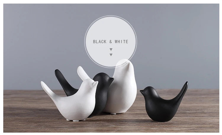 Set of black and white ceramic birds on a wooden surface with a gray background.