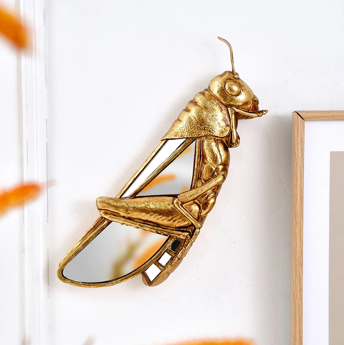 Gold insect-shaped mirror on a white wall