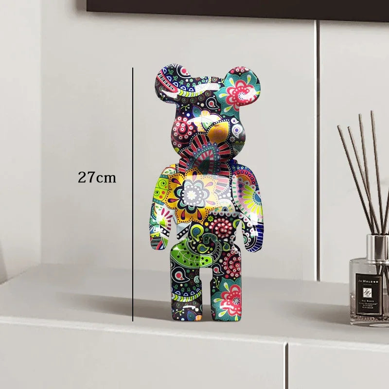 Colorful decorative bear figure on a white surface with a vase in the background
