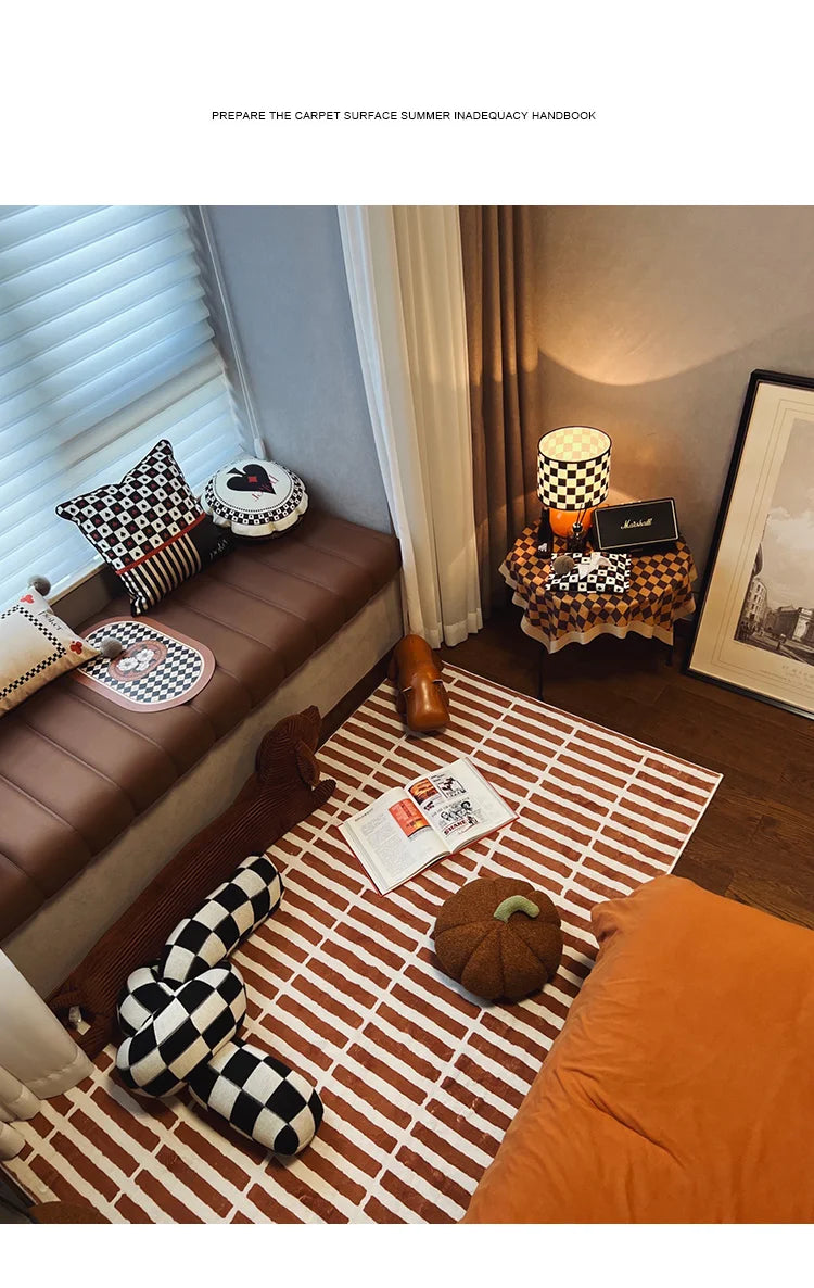 Cozy living room with a brown sofa, checkered pillow, and striped rug.