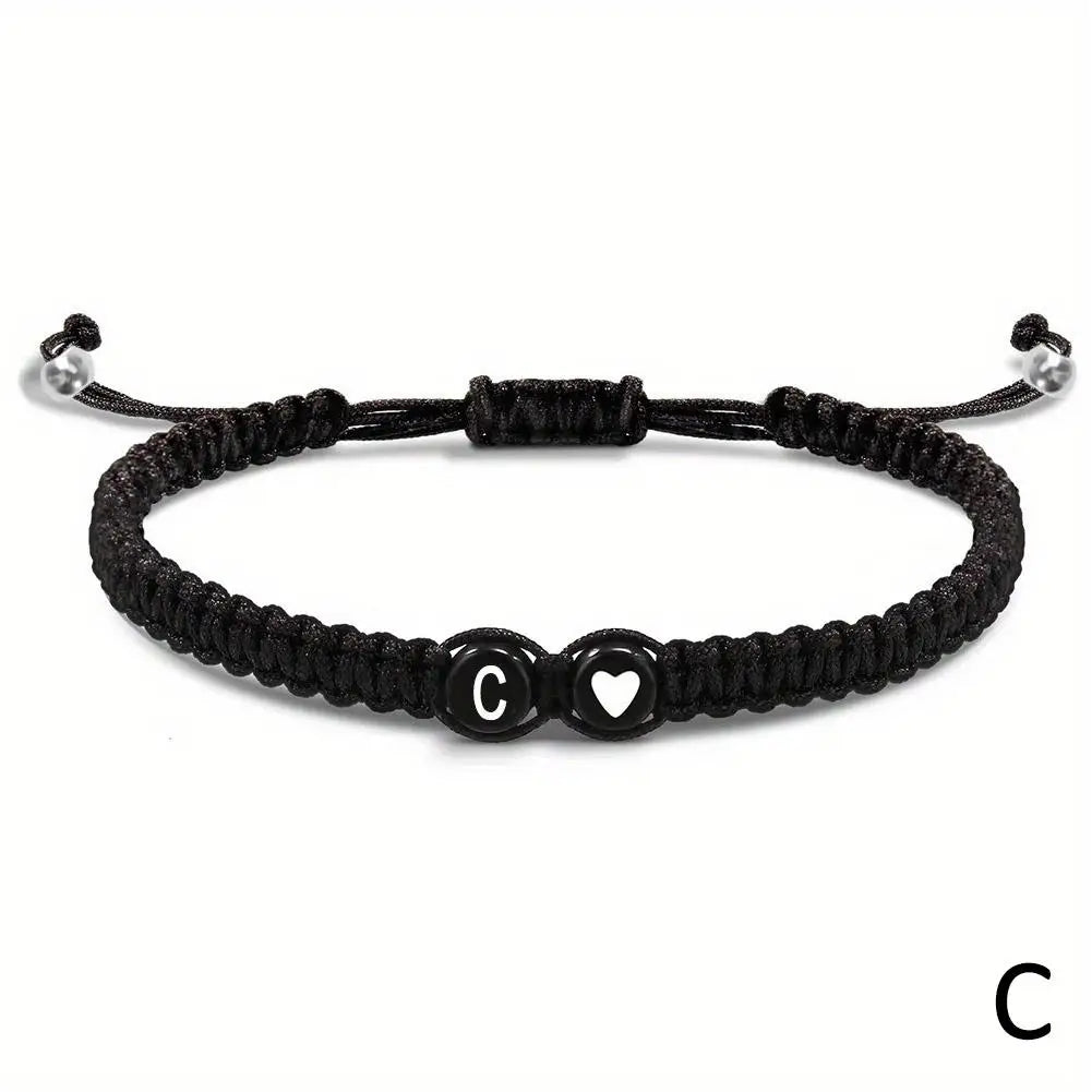 Black braided bracelet with heart and circle charm on a white background