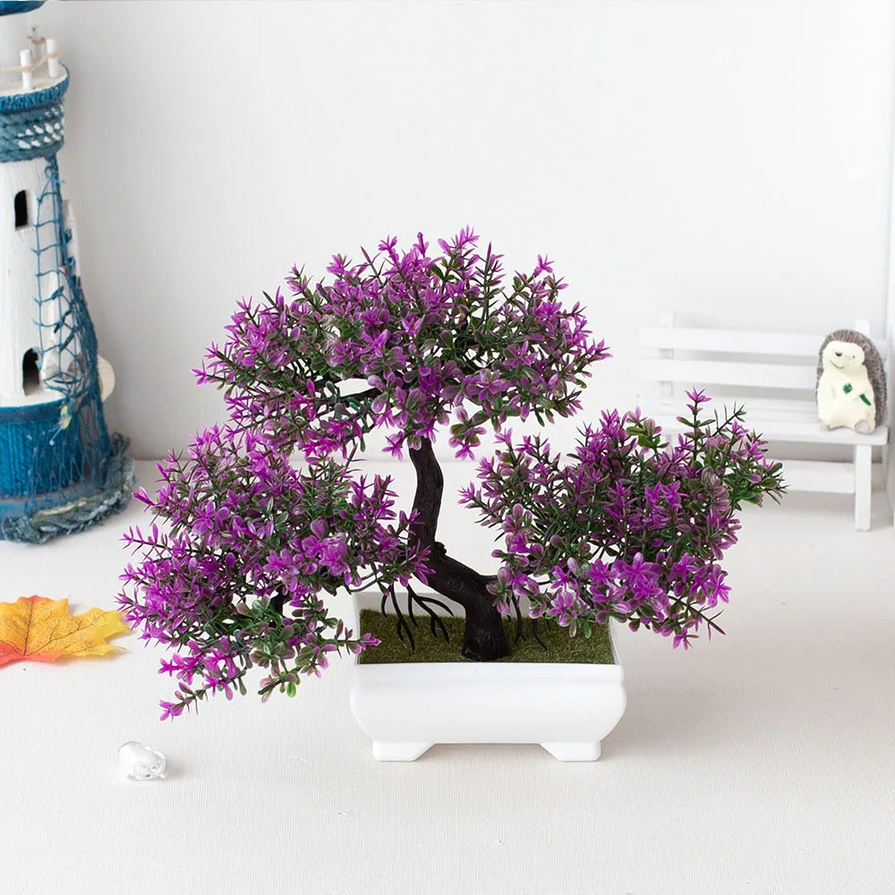 Artificial bonsai tree with purple flowers in a white pot on a light surface.