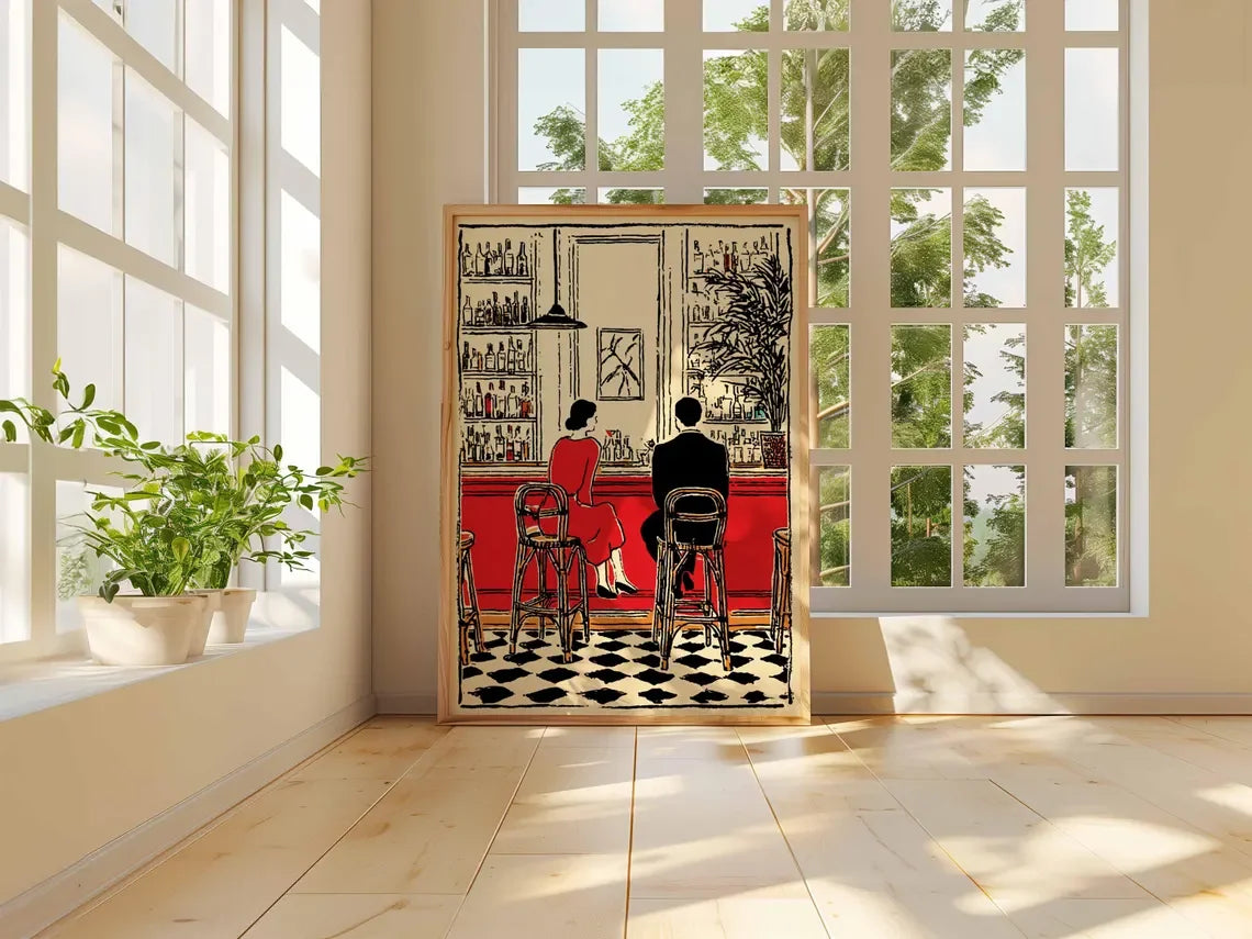 A framed art print depicting a retro-style bar scene with a woman in a red dress and a man sitting at a counter, leaning against a wall in a bright, modern room with large windows and plants.