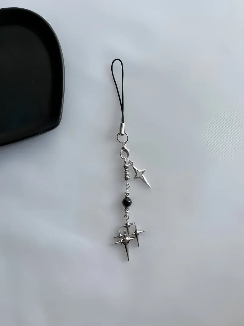 Phone charm with star and nail design on a light gray background