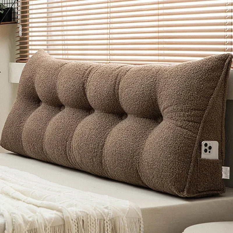 Brown wedge-shaped pillow on a bed with a neutral background