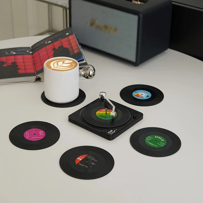 Record-shaped coasters on a table with a cup of coffee and a turntable.