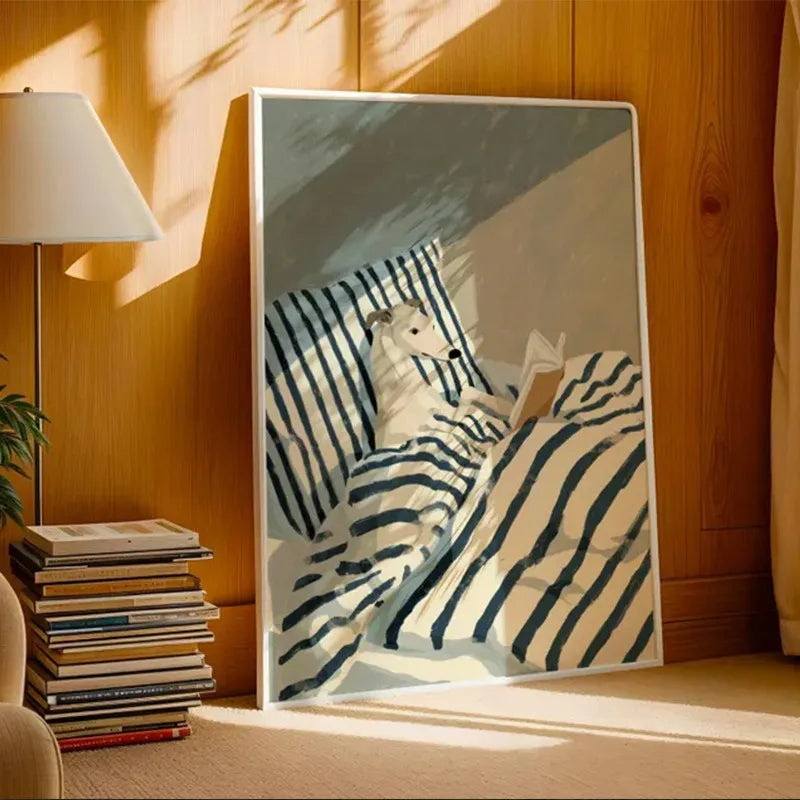 Framed artwork of a dog lying on a striped blanket in a cozy room with books and a lamp.