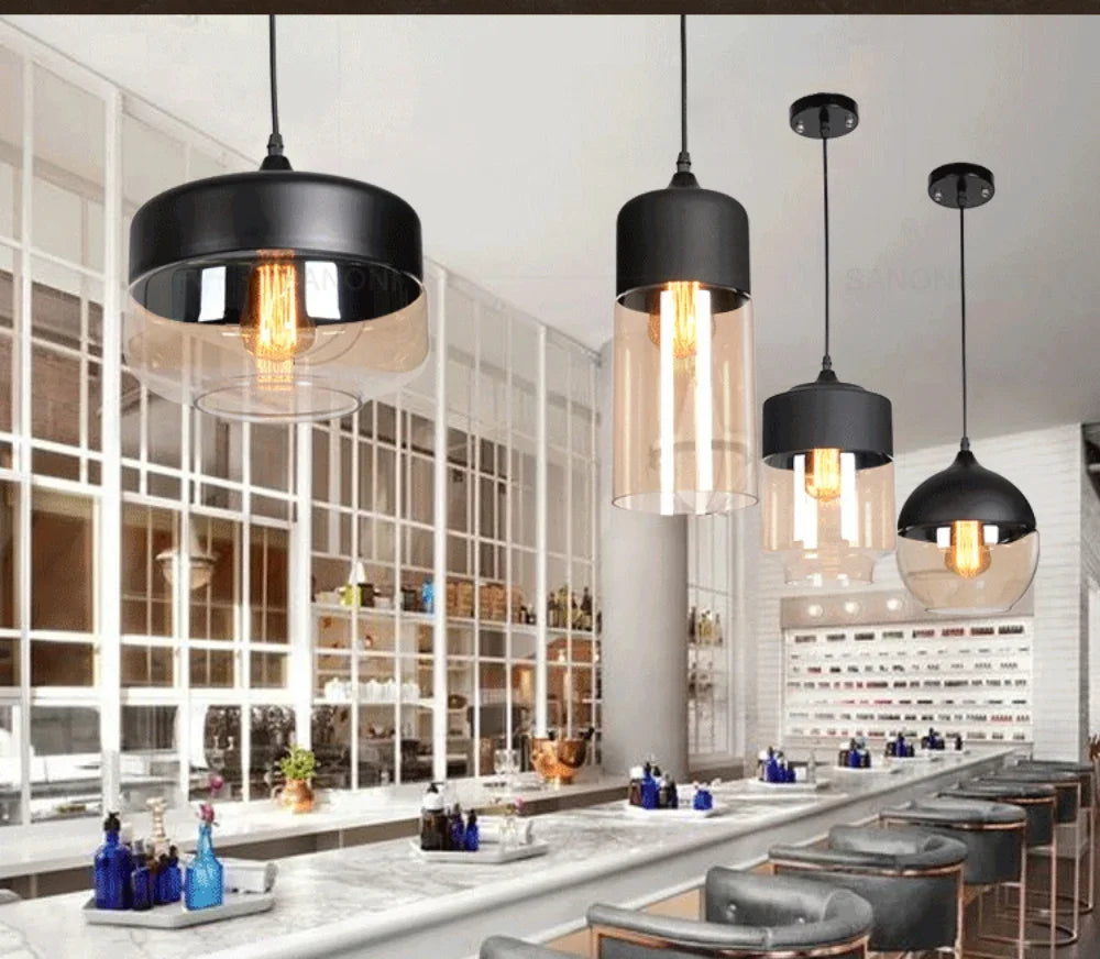 Modern bar interior with black pendant lights and a long counter.