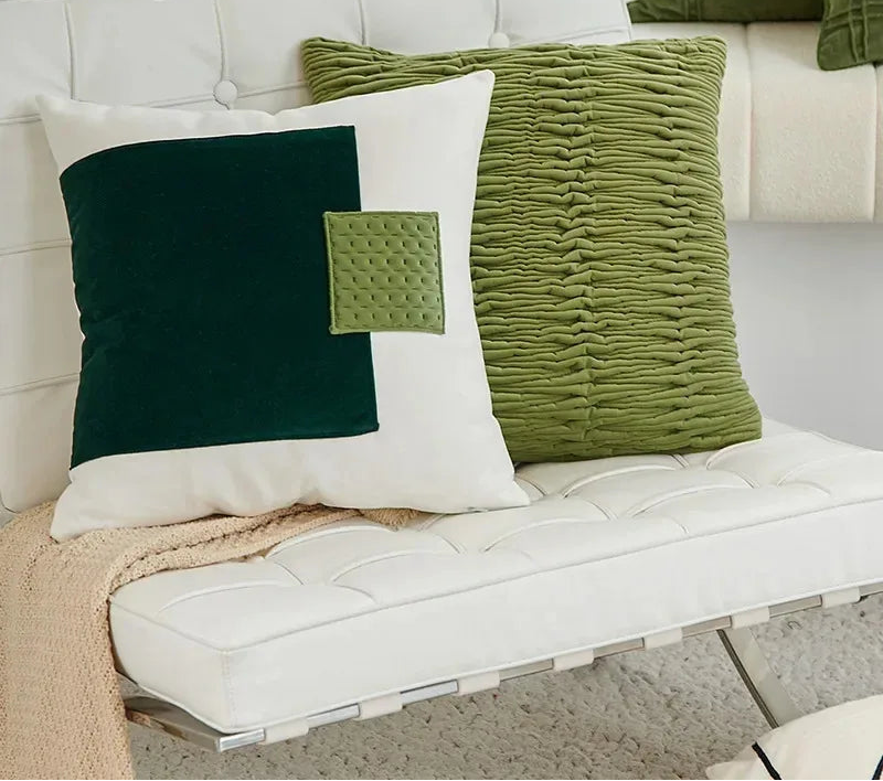 Green and white textured pillows on a white sofa with a neutral blanket.
