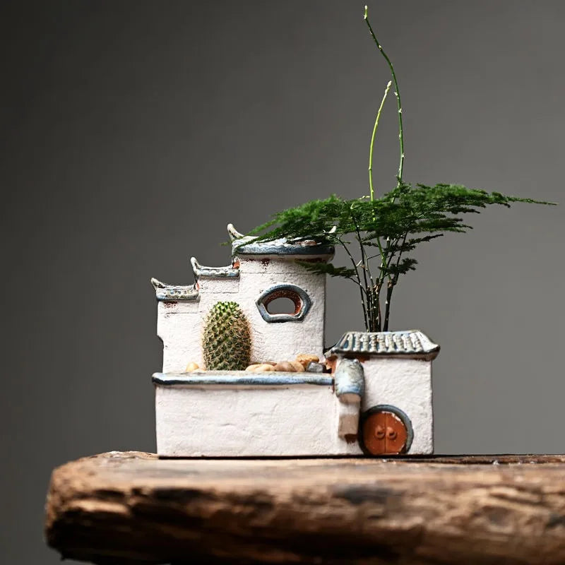 Decorative miniature house with plants on a wooden surface and gray background
