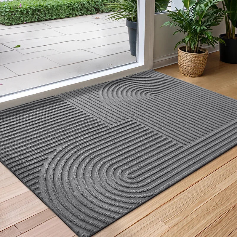 Gray doormat with wavy pattern on a wooden floor, leading to a glass door.