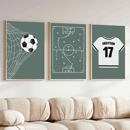 Three framed sports-themed wall art prints displayed above a beige sofa. The prints feature a soccer ball with a net graphic, a soccer field tactical diagram, and a white soccer jersey with 'GRAYSON 17' on the back.