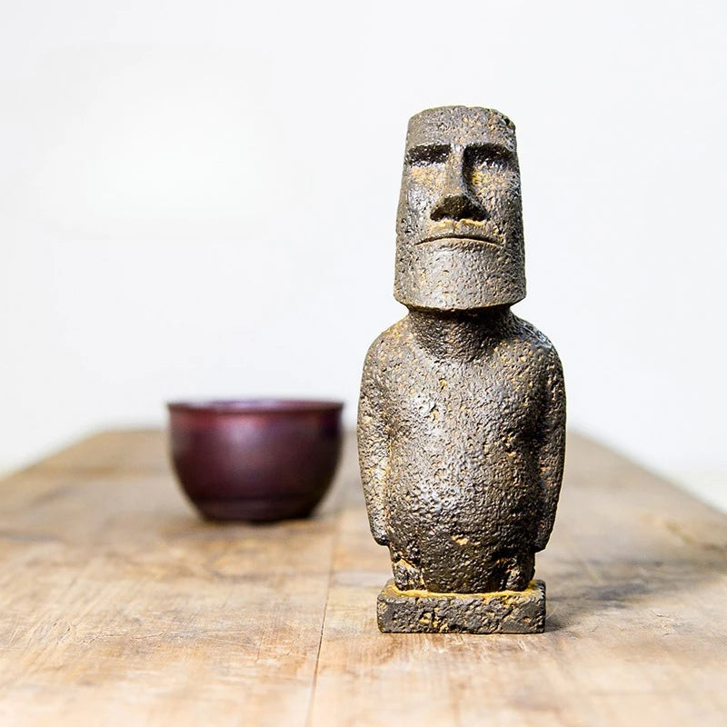 Moai-inspired resin ornament with a distressed stone-effect finish displayed on a wooden surface.