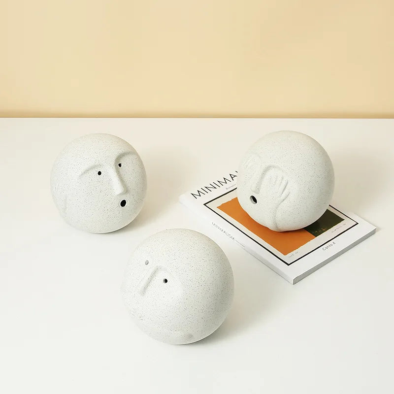 Three white ceramic sheep figurines on a light surface with a magazine underneath.