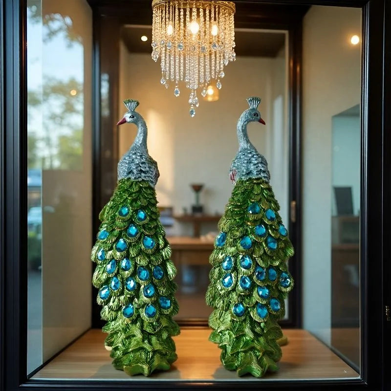 Two decorative peacock statues in a room with a chandelier.