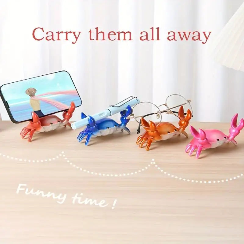 Colorful toy crabs on a wooden surface with a phone displaying a beach scene.
