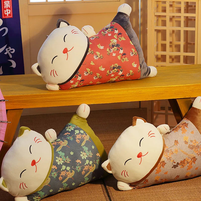 Three cat-shaped cushions with floral patterns on a wooden shelf.