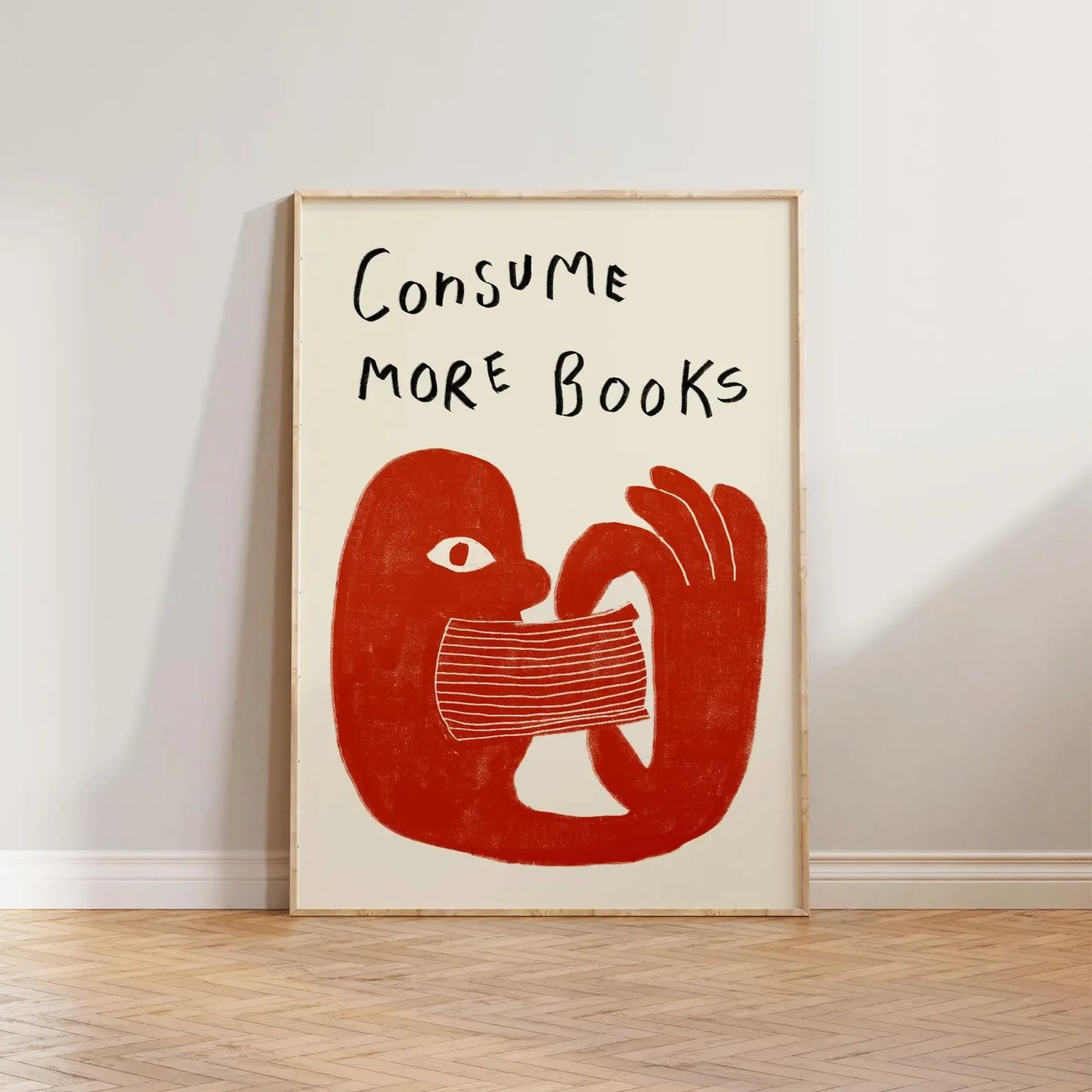 Framed artwork with a red abstract design and text 'Consume More Books' on a white wall.