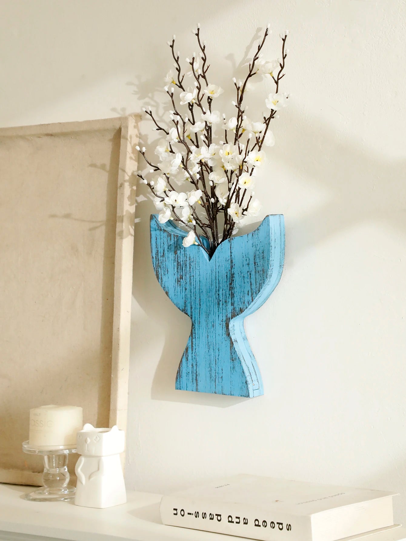 Decorative whale tail wall vase with white flowers on a light background