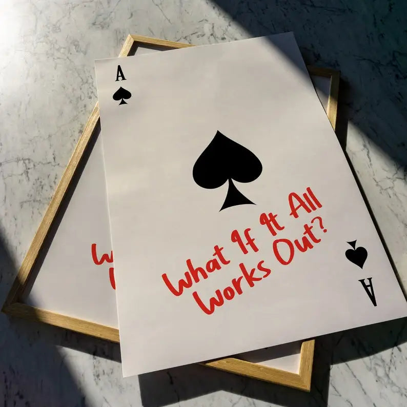 Playing cards with ace of spades design and text 'What If It All Works Out?' on a marble surface.
