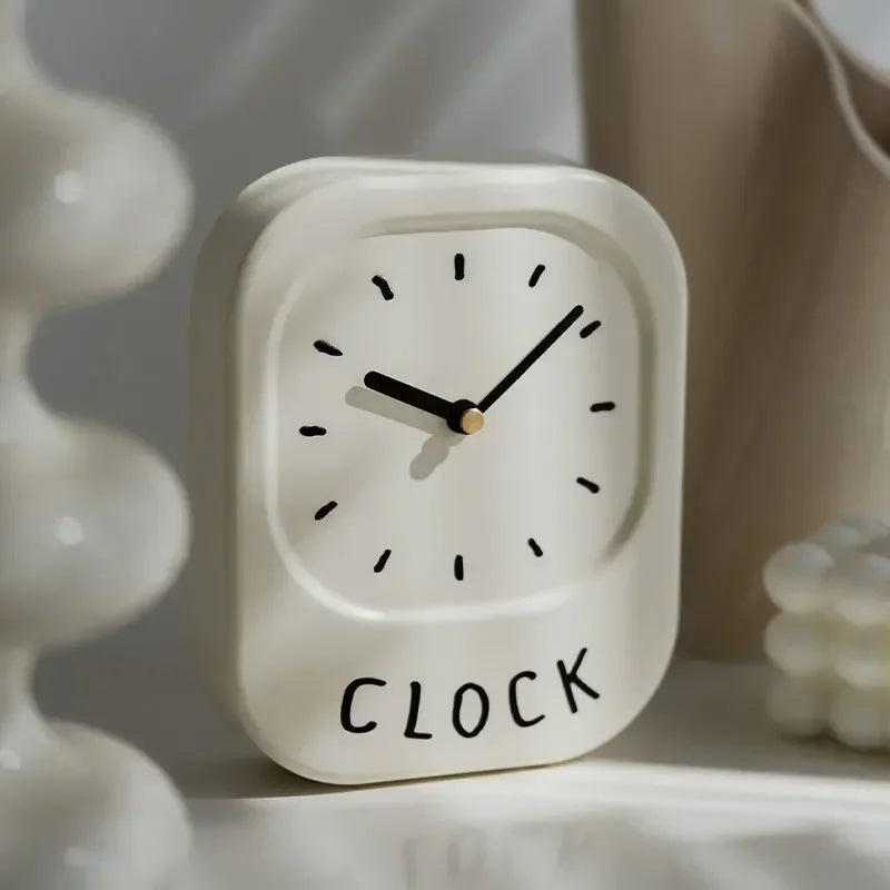 Small white clock with 'CLOCK' text on a neutral background