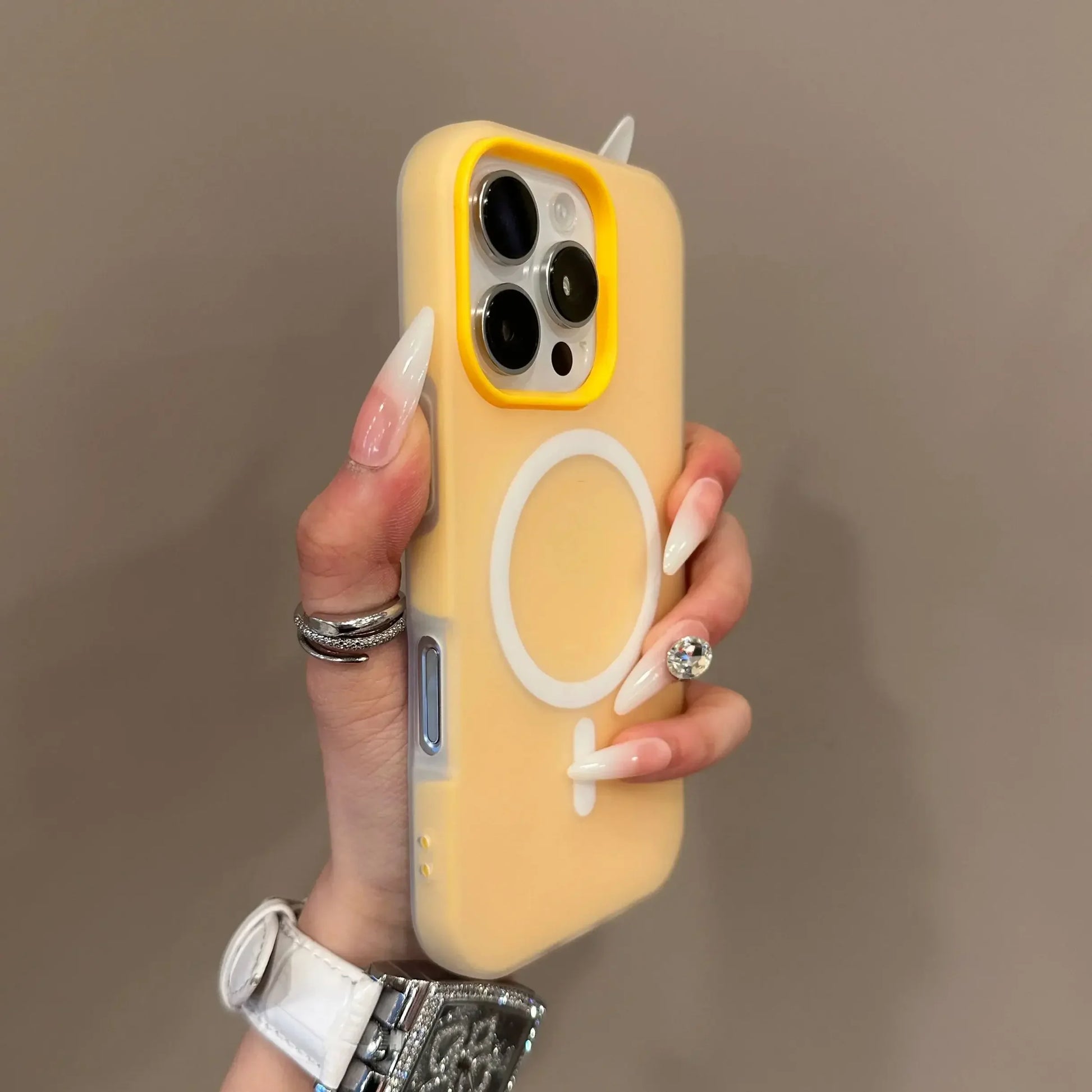 Hand holding a phone with a yellow case featuring a female symbol on a brown background