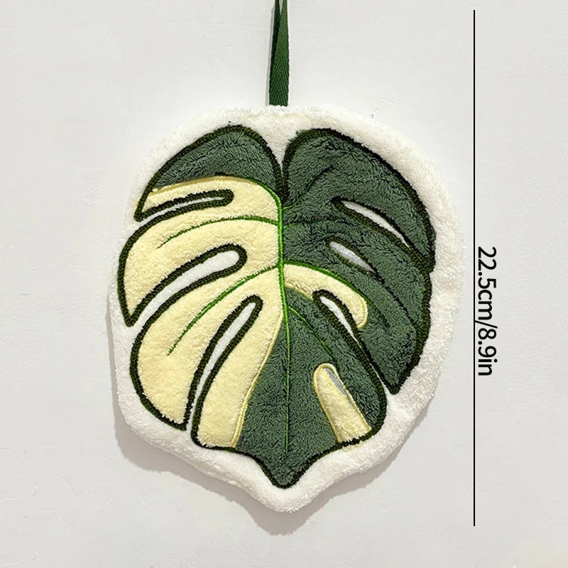 Decorative leaf-shaped towel with green and white colors on a light gray background